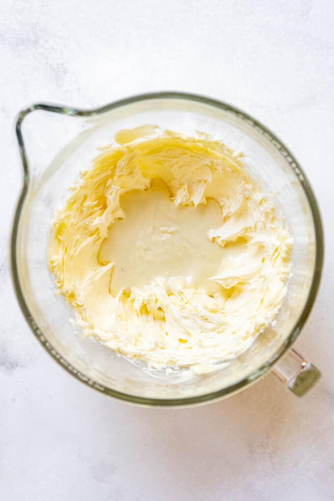Creamed butter in a bowl with melted white chocolate.