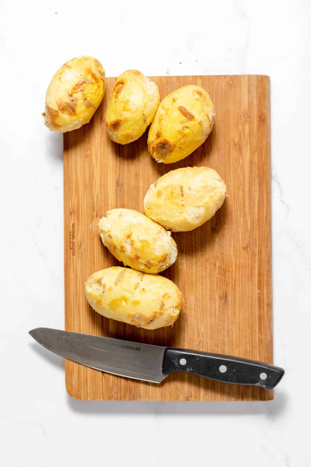 Peeled baked potatoes on a cutting board.