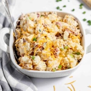 A white serving dish of loaded baked potato salad.