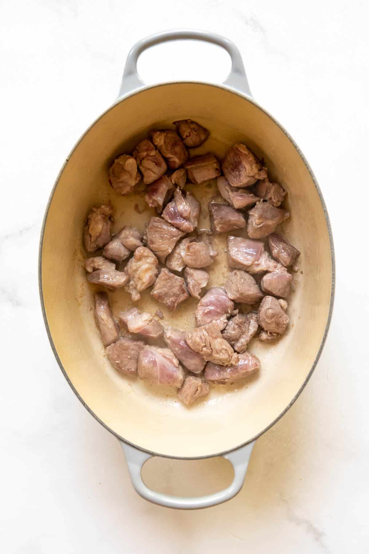 Top view of a casserole dish with pork pieces in it.