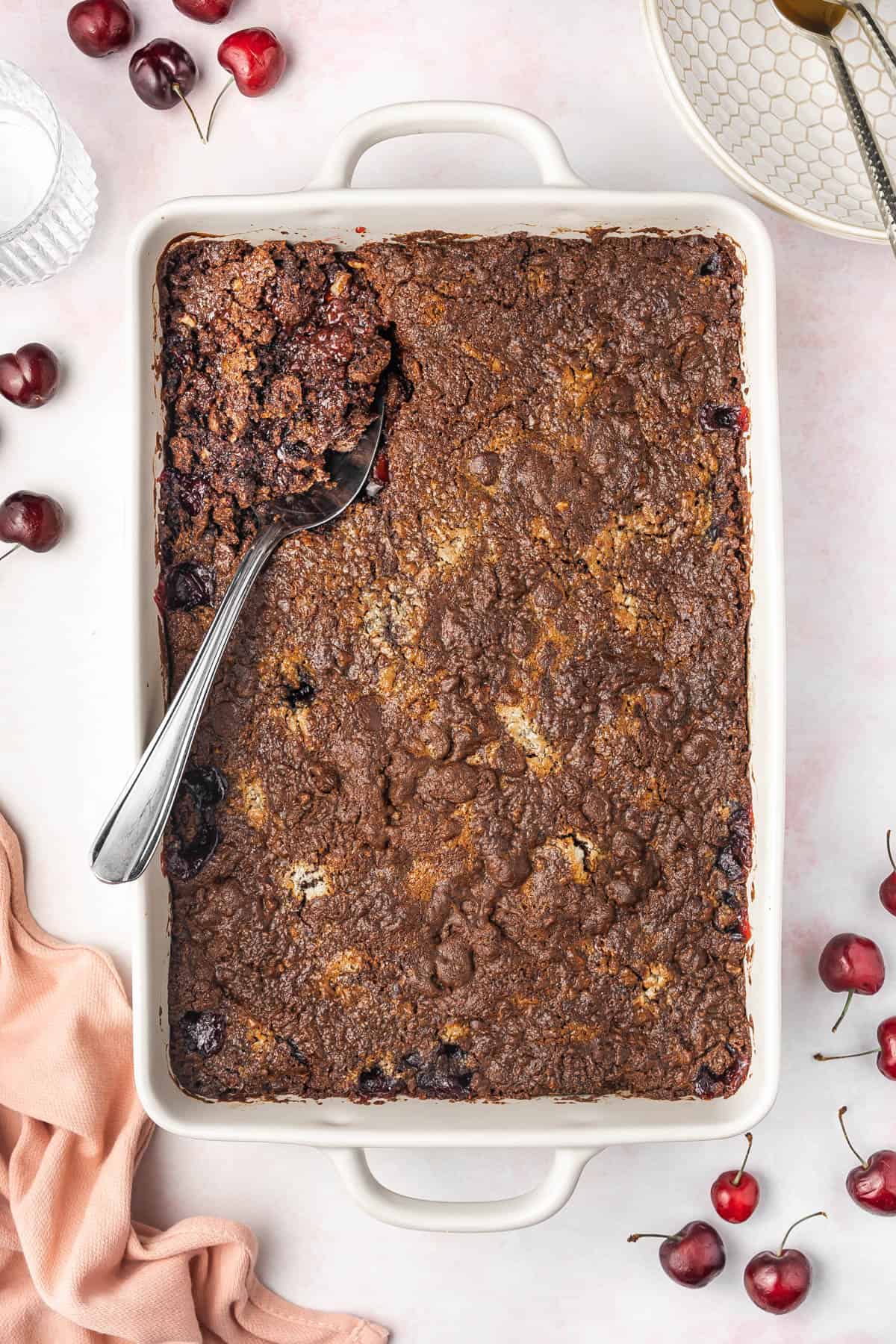 Baked chocolate cherry dump cake with a serving spoon in it.