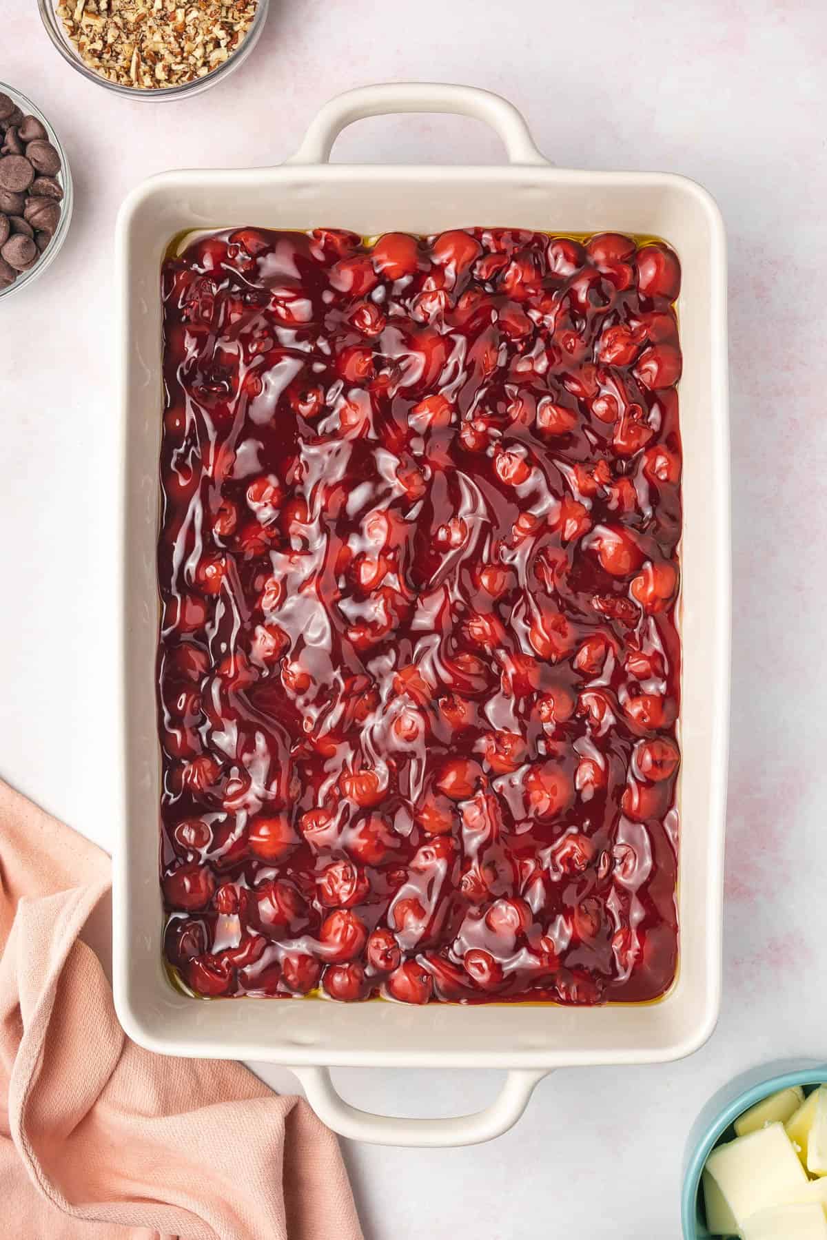 Spreading cherry pie filling into a single layer in a baking dish.