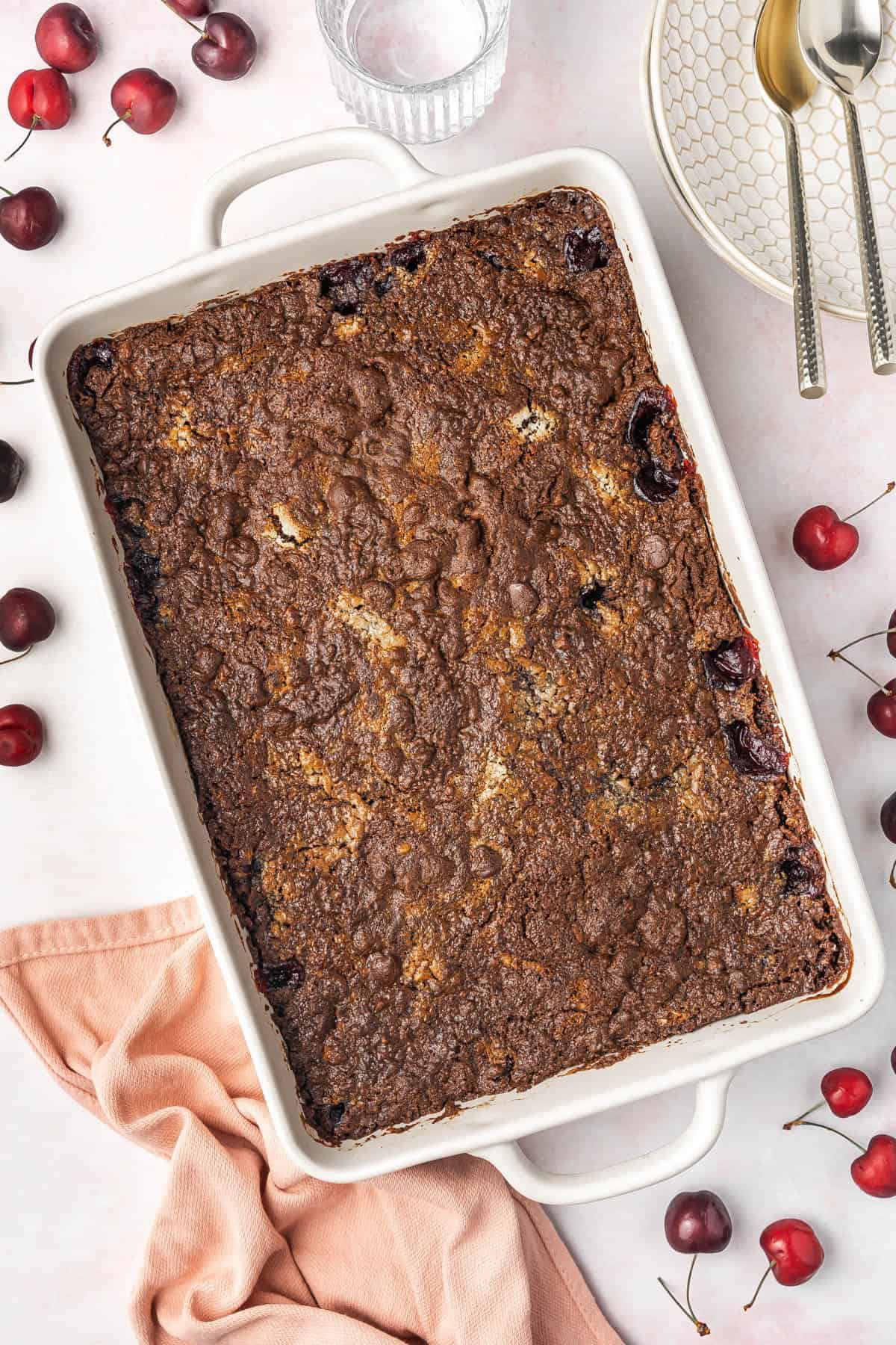 An overhead image of a chocolate cherry dump cake in a white 9x13-inch pan.
