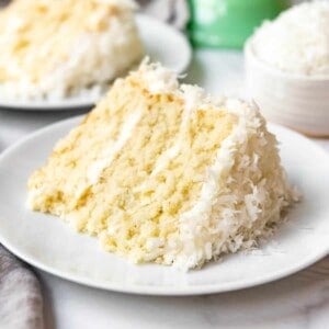 Close up of a slice of freshly baked coconut cake made from scratch on a white plate.