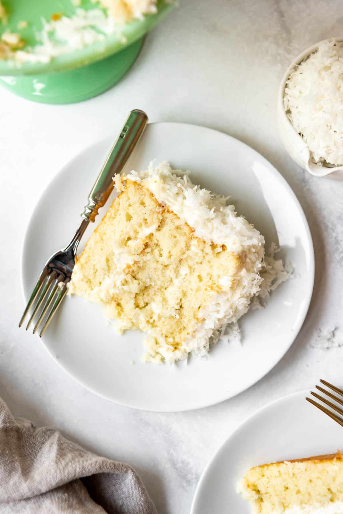 Top view of from scratch coconut cake on a white plate with a fork.