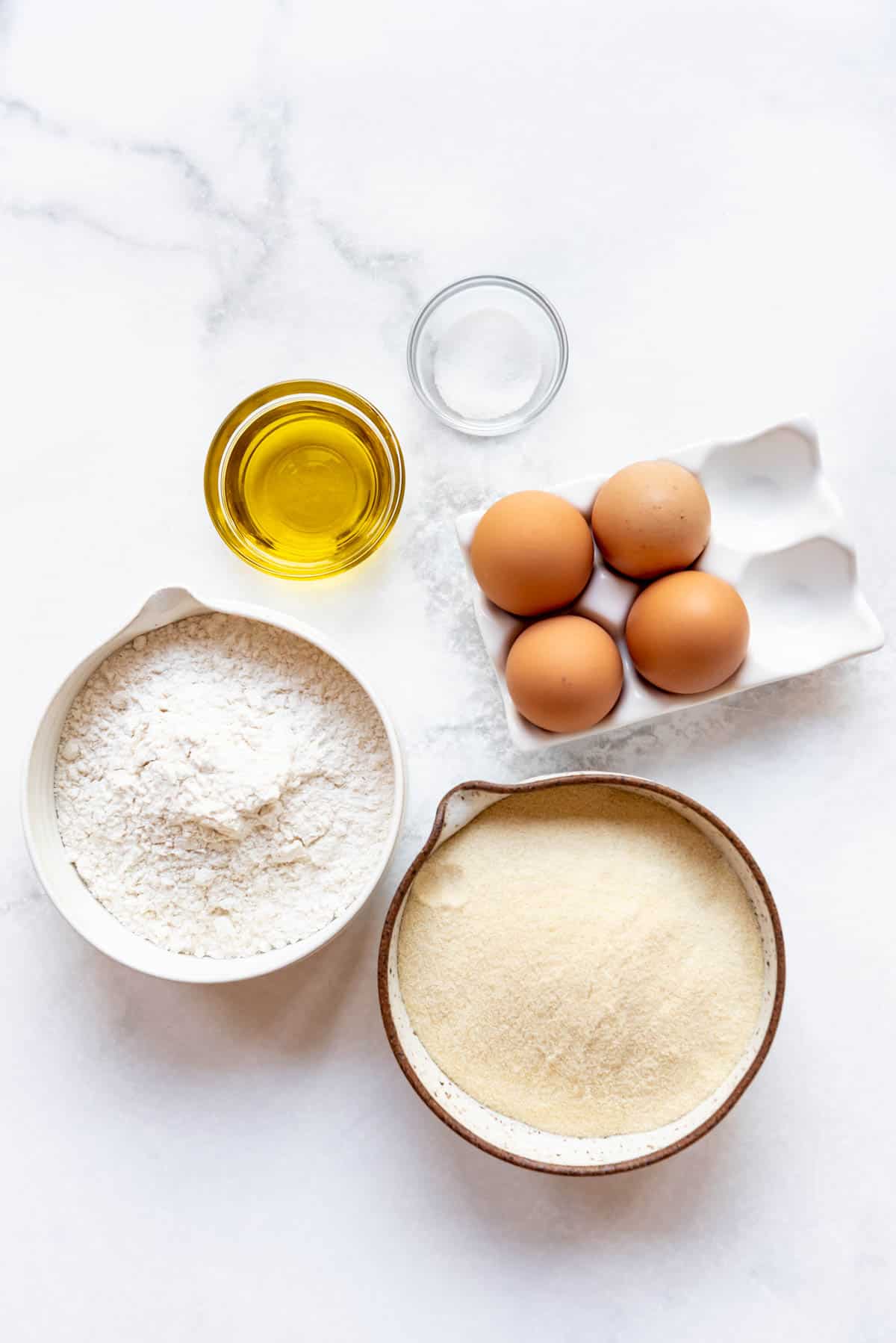 All-purpose flour, semolina flour, four eggs, olive oil, and salt for making homemade pasta.