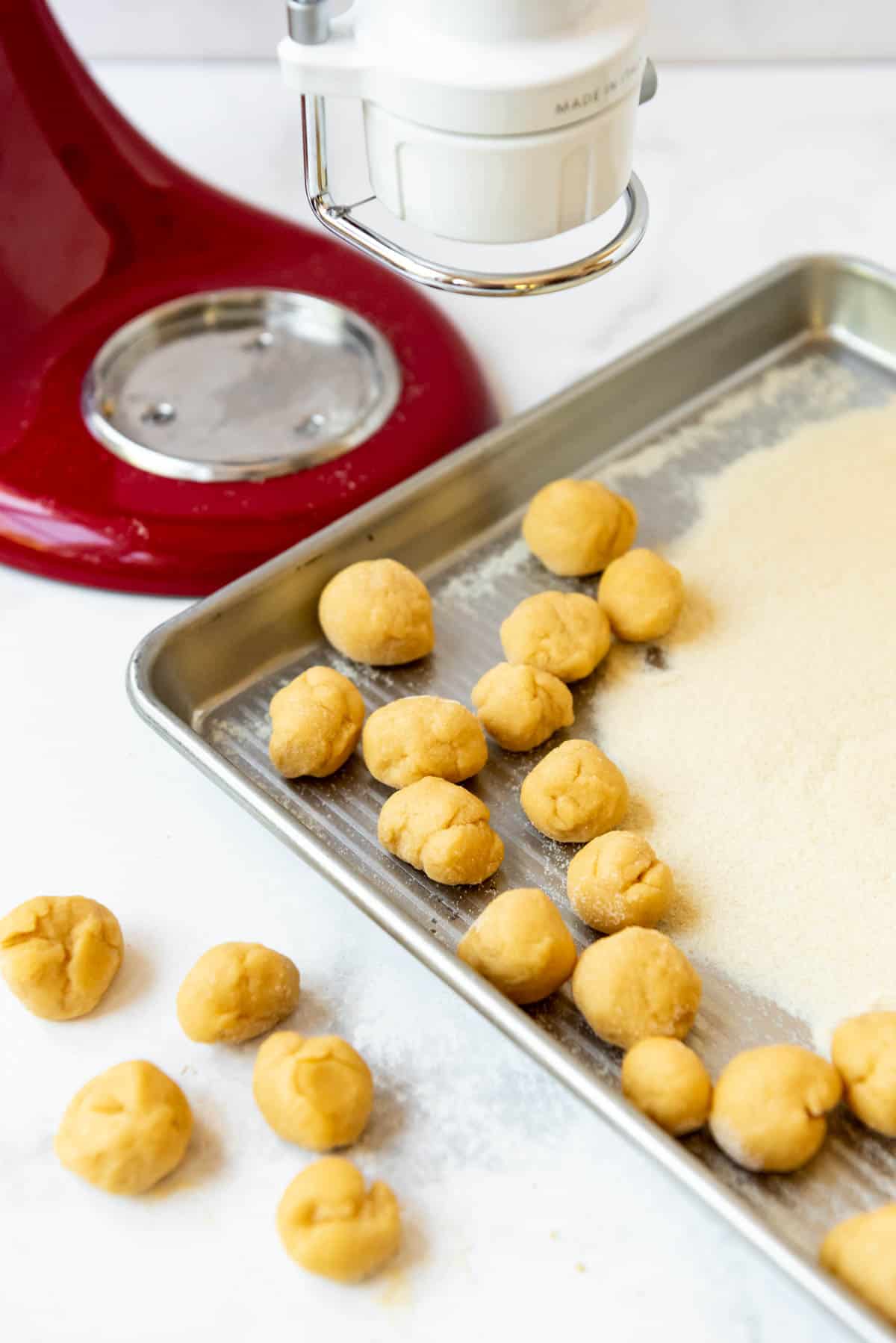Walnut sized balls of pasta dough next to semolina flour.