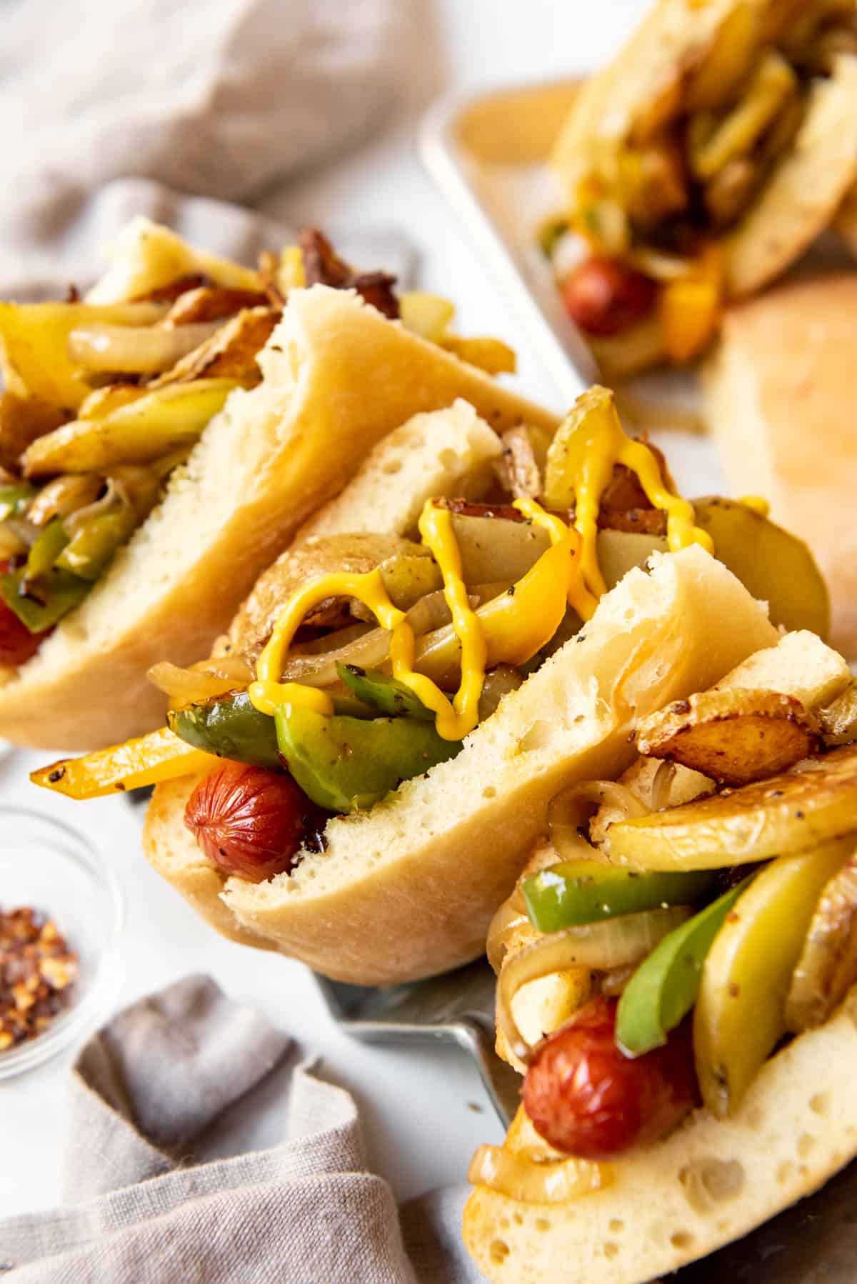 Homemade New Jersey Italian hot dogs topped with peppers, onions, potatoes, and yellow mustard.