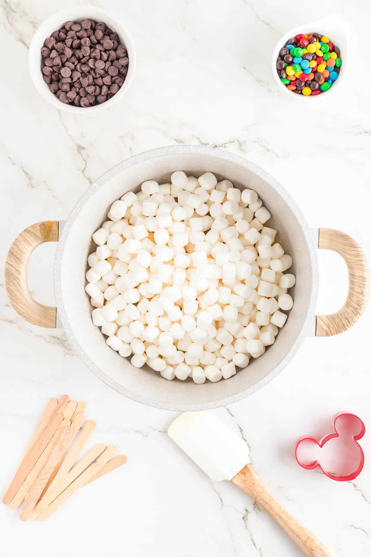 Adding mini marshmallows to melted butter in a large pot.