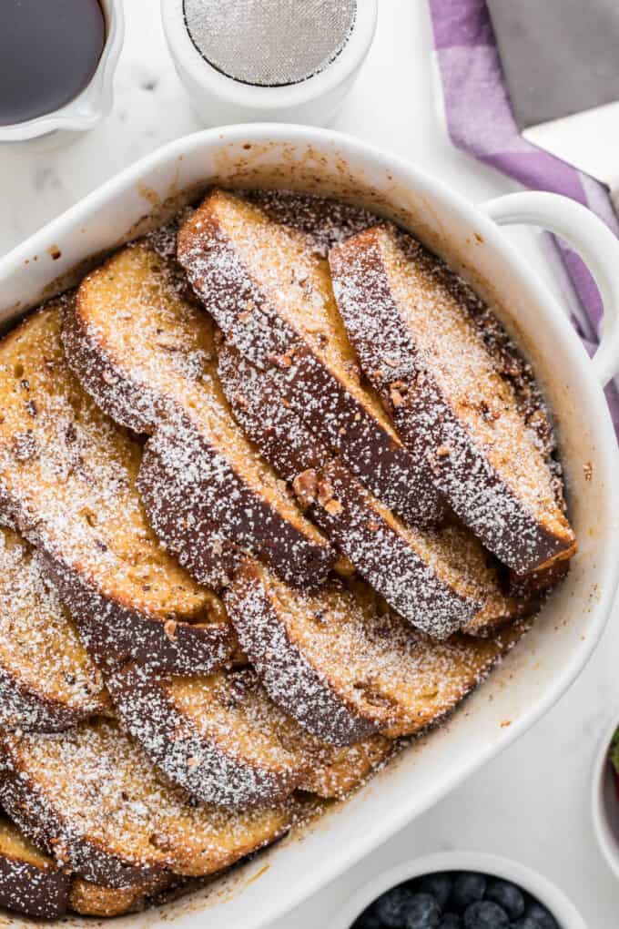 A close image of baked overnight French toast dusted with powdered sugar.