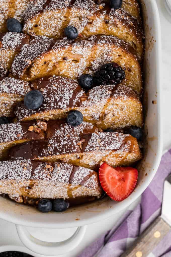 Overnight French toast dusted with powdered sugar and drizzled with maple syrup.