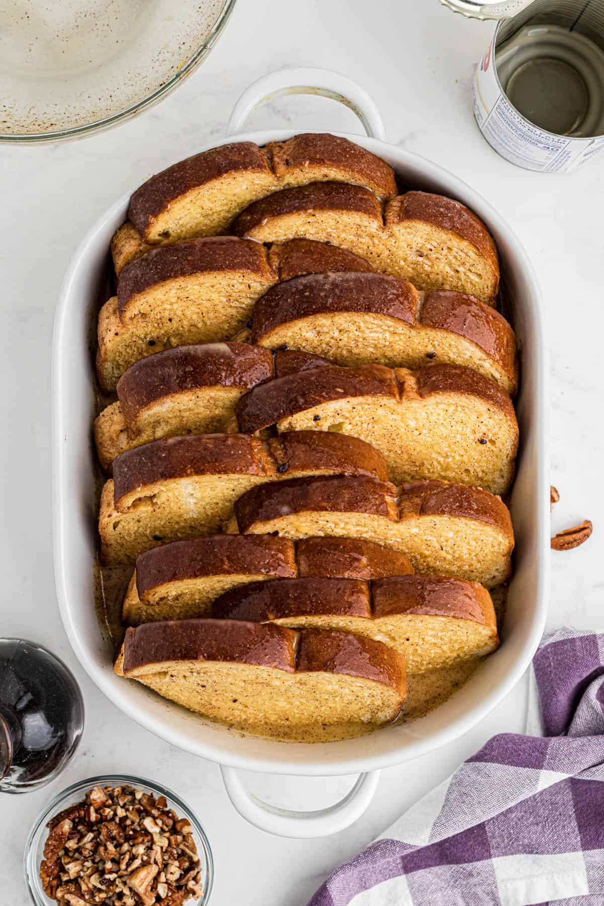 Slices of bread in a baking dish with egg custard mixture poured over the top.