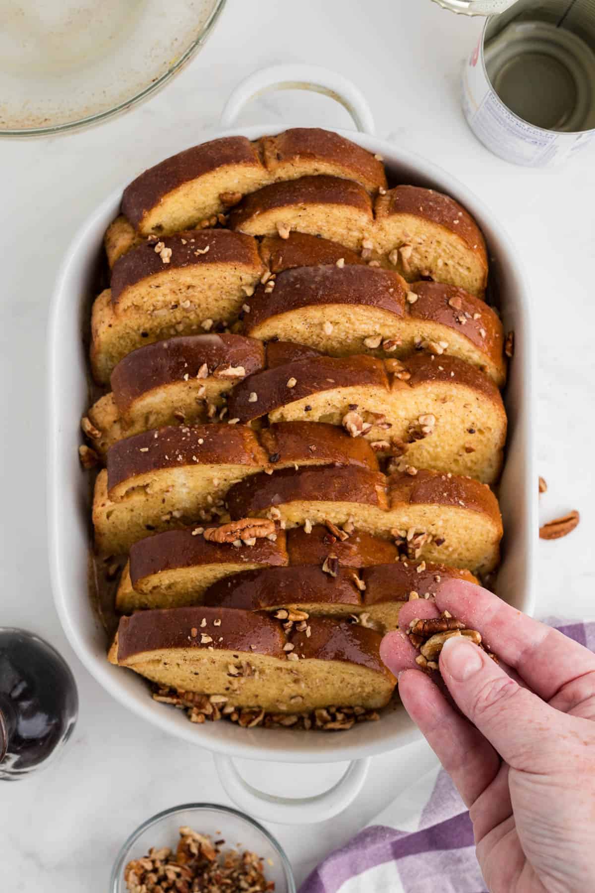 Sprinkling chopped pecans over french toast casserole. 