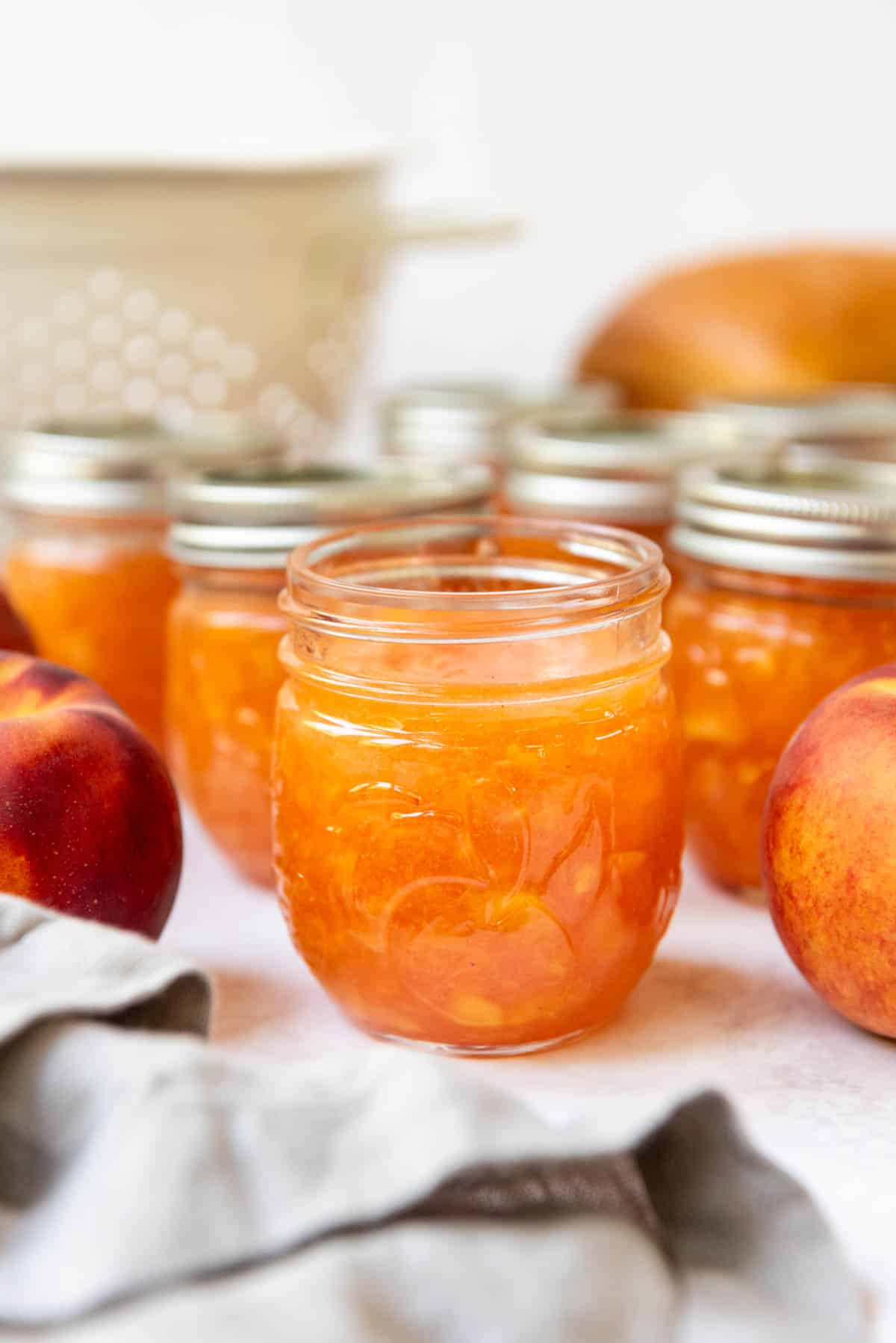 Jars of peach jam with the front jar opened.