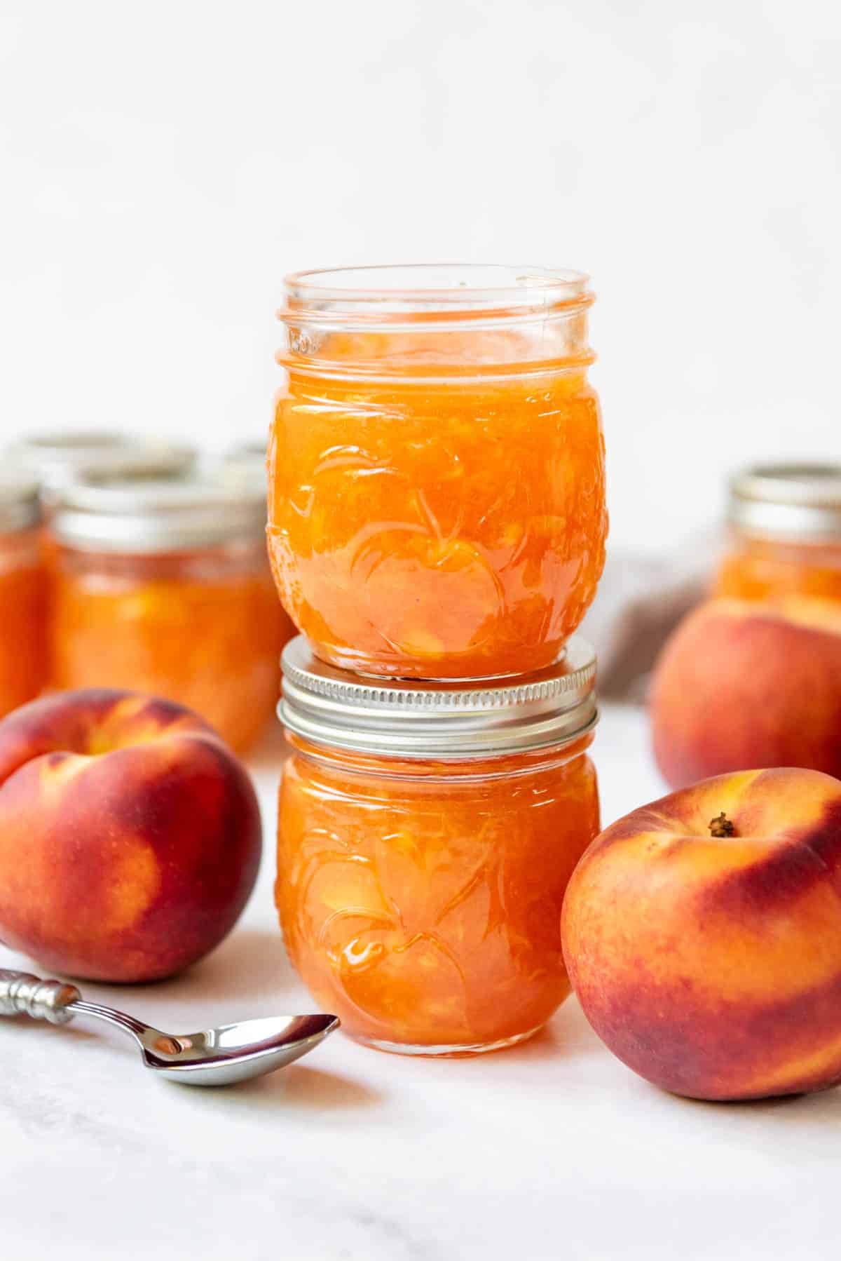An image of two jars of peach jam stacked on top of each other.