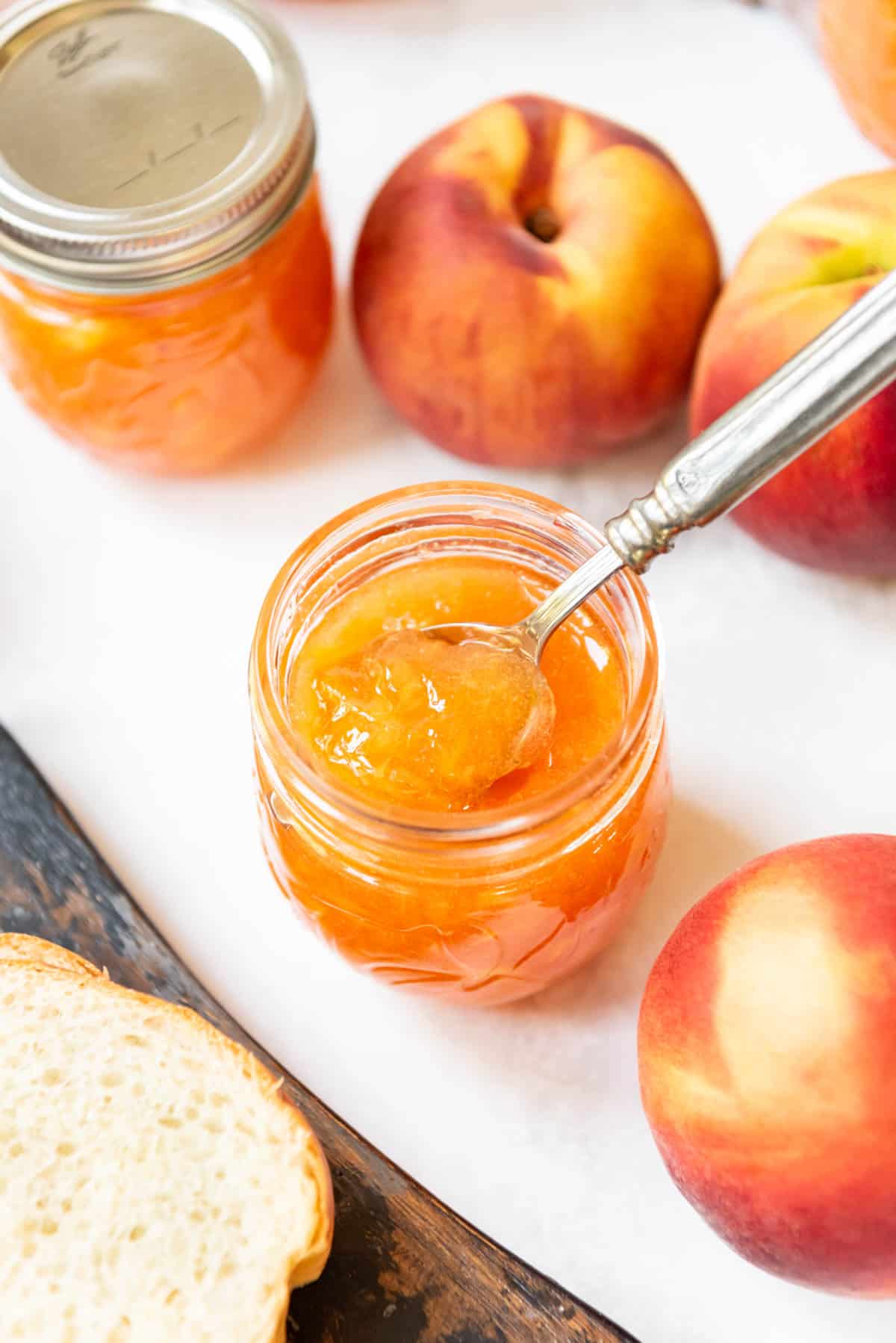 A spoon in a jar of peach jam.