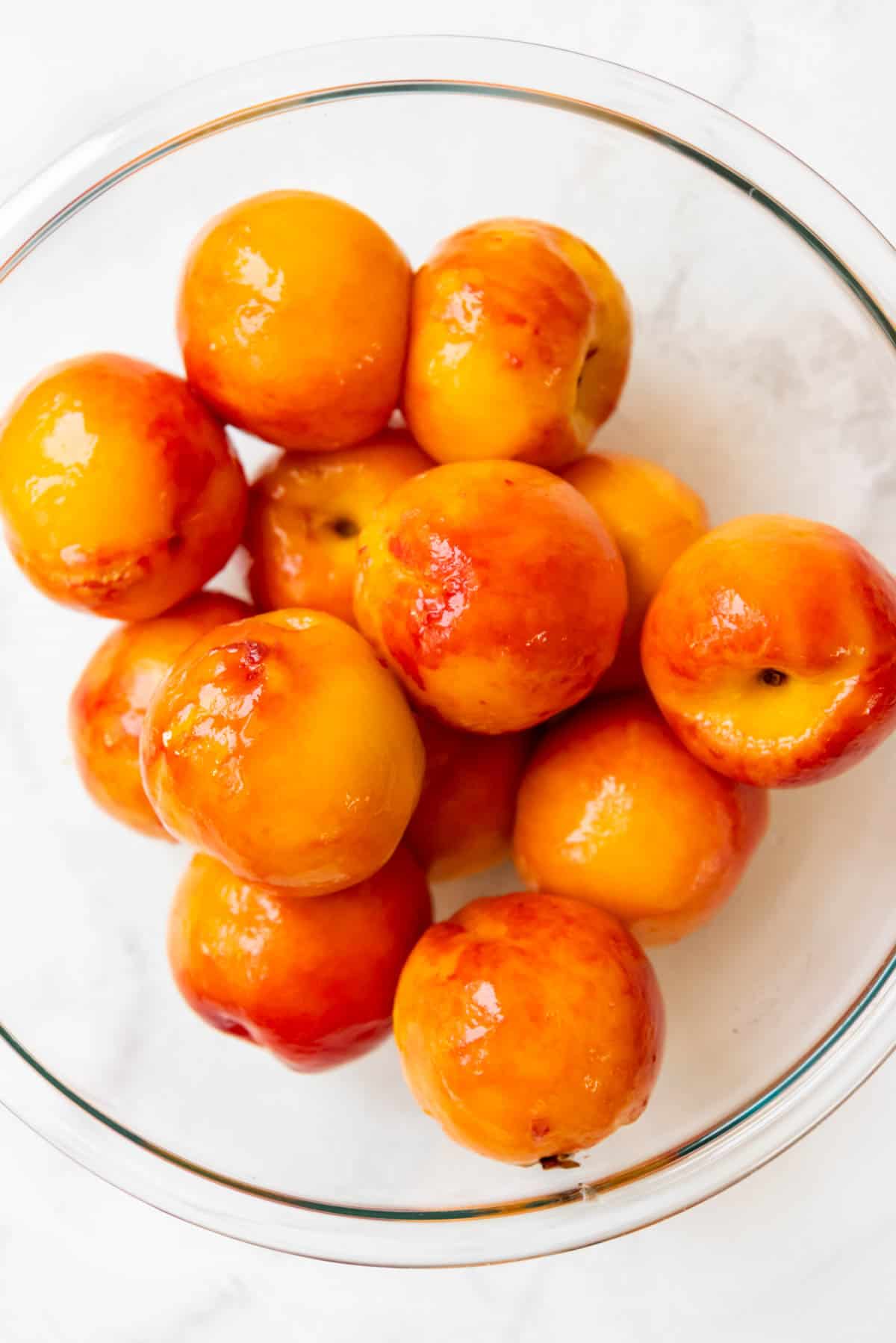 A bowl full of peeled peaches.