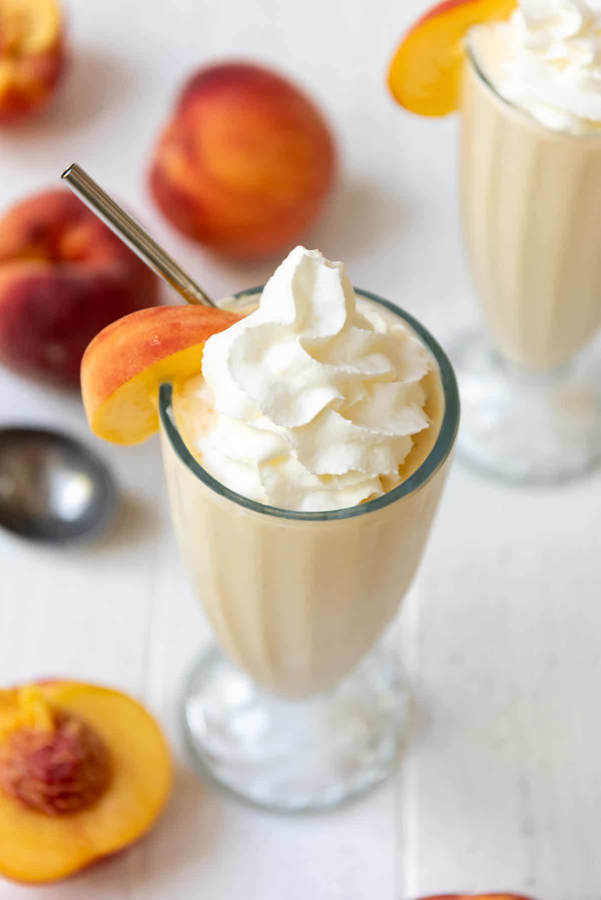 An overhead image of peach milkshakes topped with whipped cream.