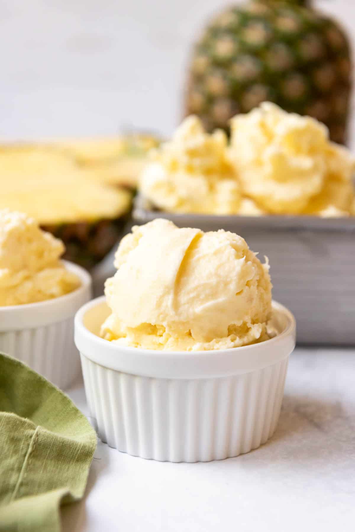 A close image of a white bowl filled with pineapple ice cream.