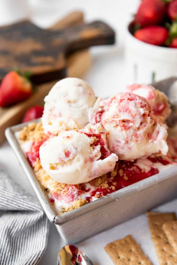 Close up of Strawberry Cheesecake Ice Cream with three scoops of the ice cream on top of the filled dish.