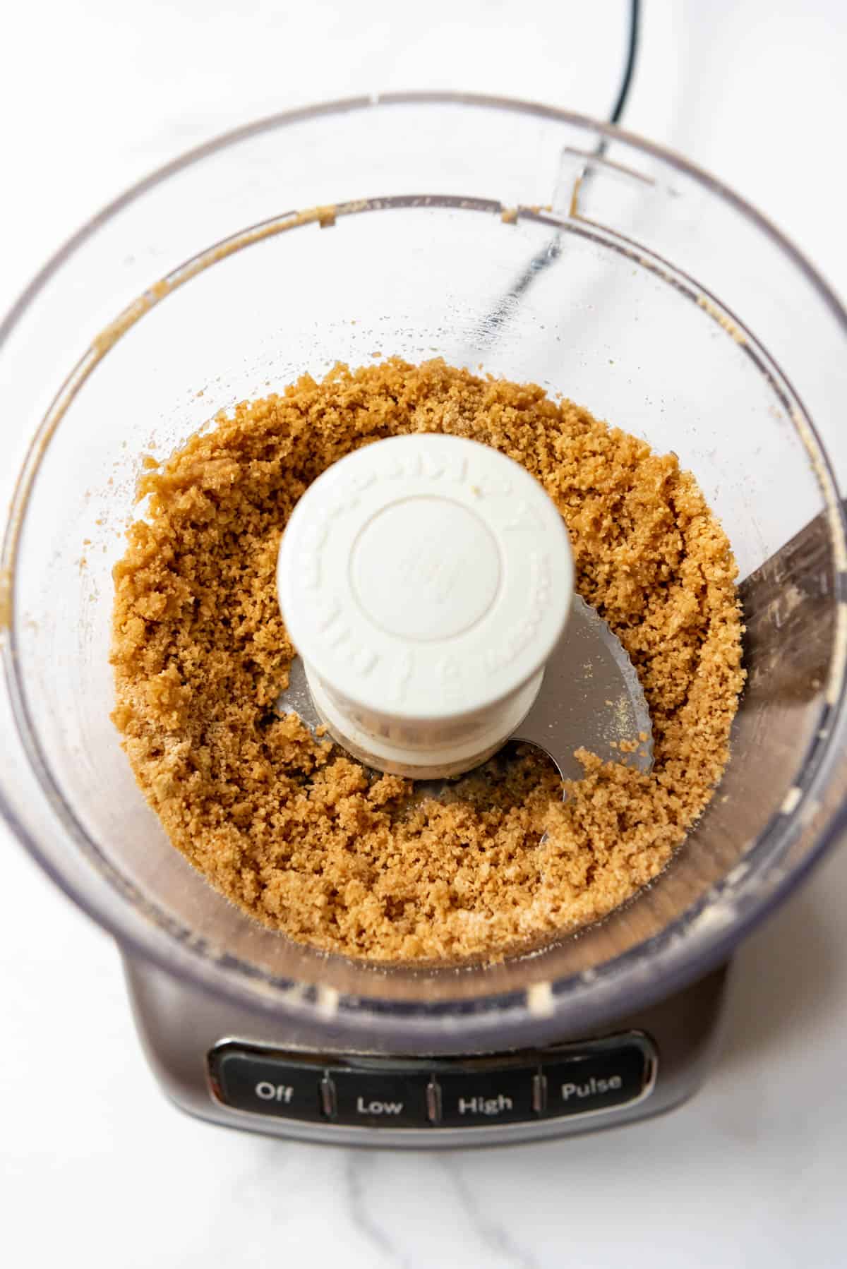 Top view of a food processor with Graham Cracker crumbs in it.