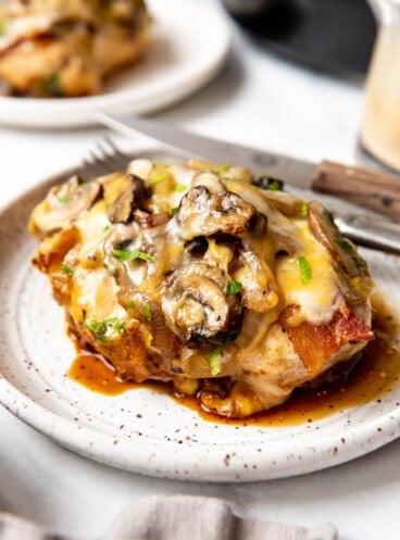 A copycat Outback Alice Springs chicken recipe on a plate with sauteed mushrooms, onions, and cheese.