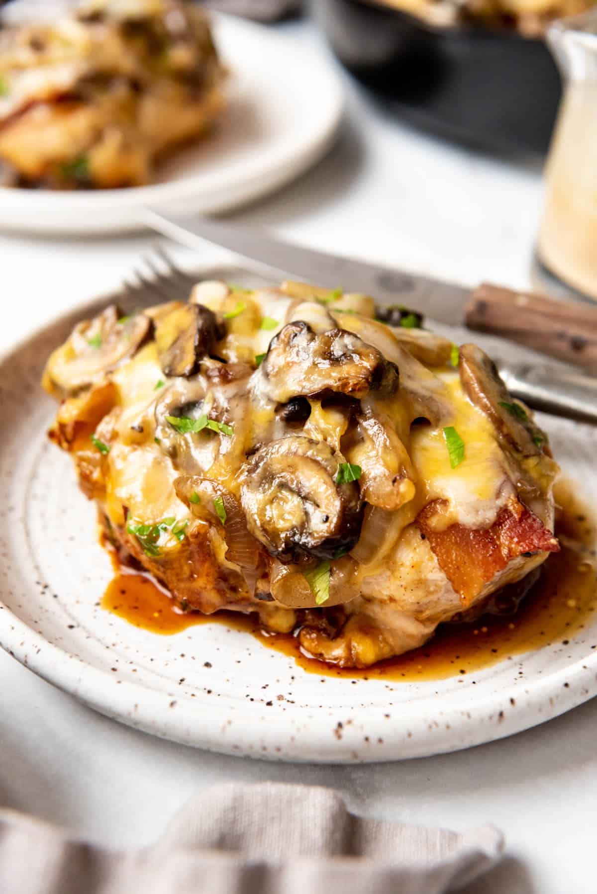 A copycat Outback Alice Springs chicken recipe on a plate with sauteed mushrooms, onions, and cheese.