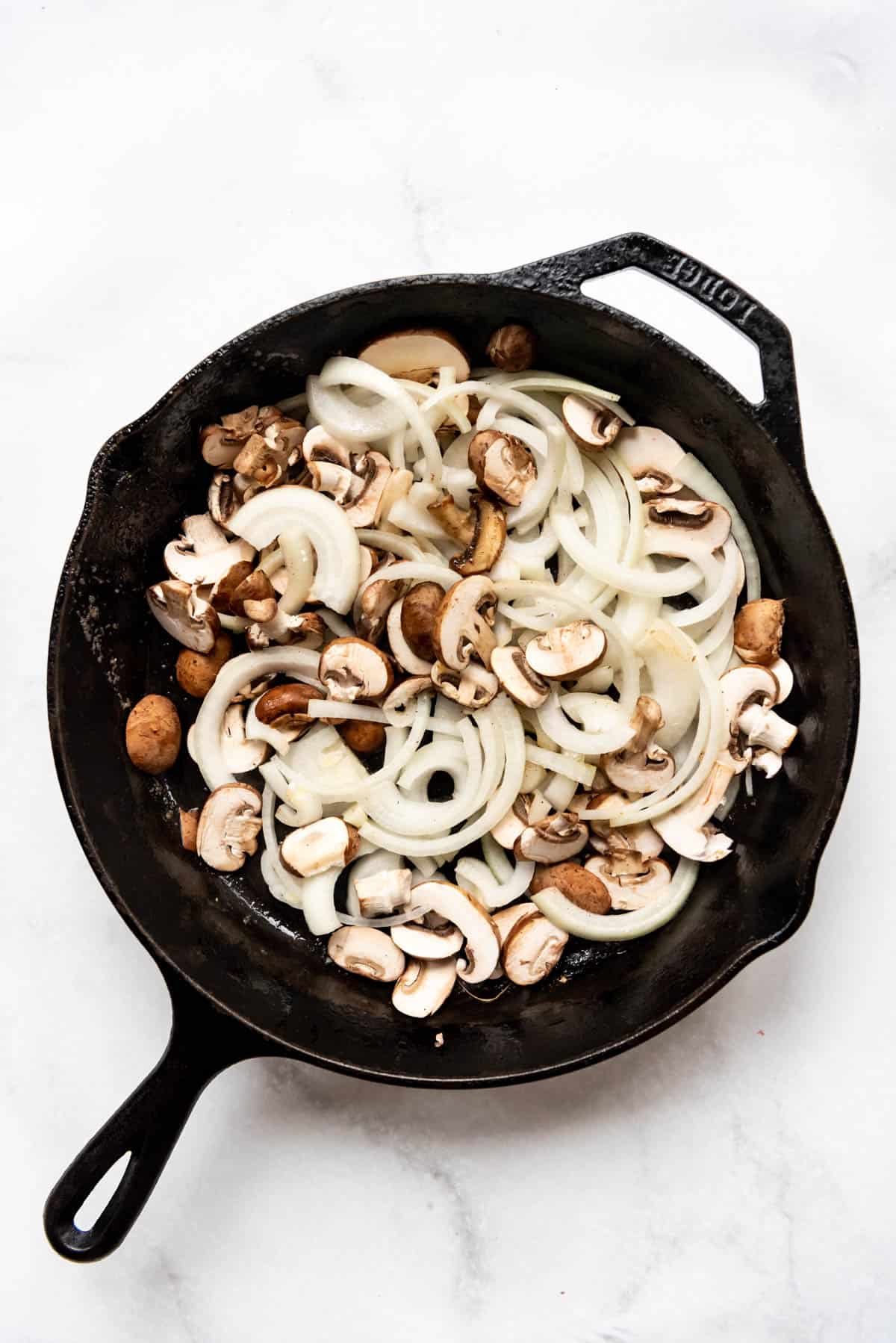 Sliced mushrooms and onions in a large pan.