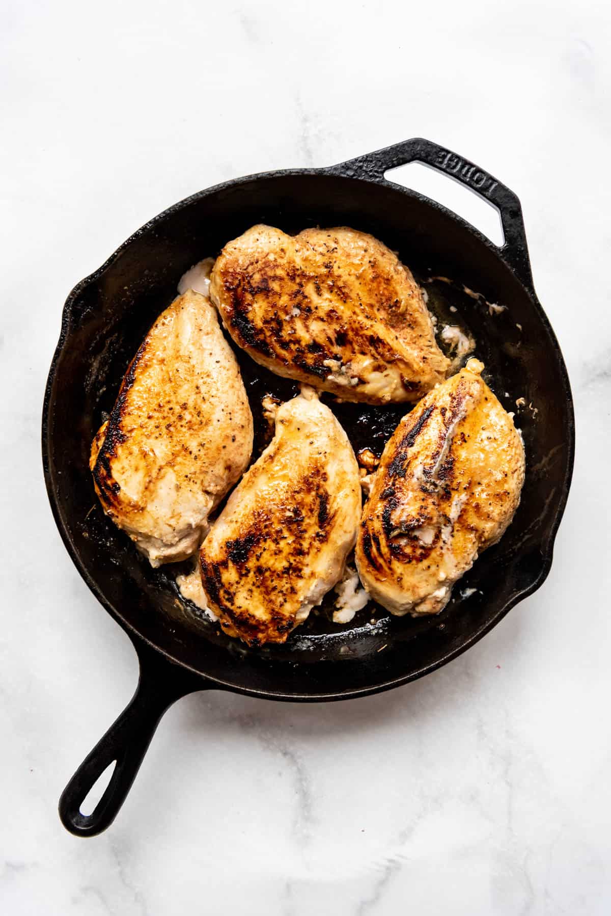 Seared chicken breasts in a pan.