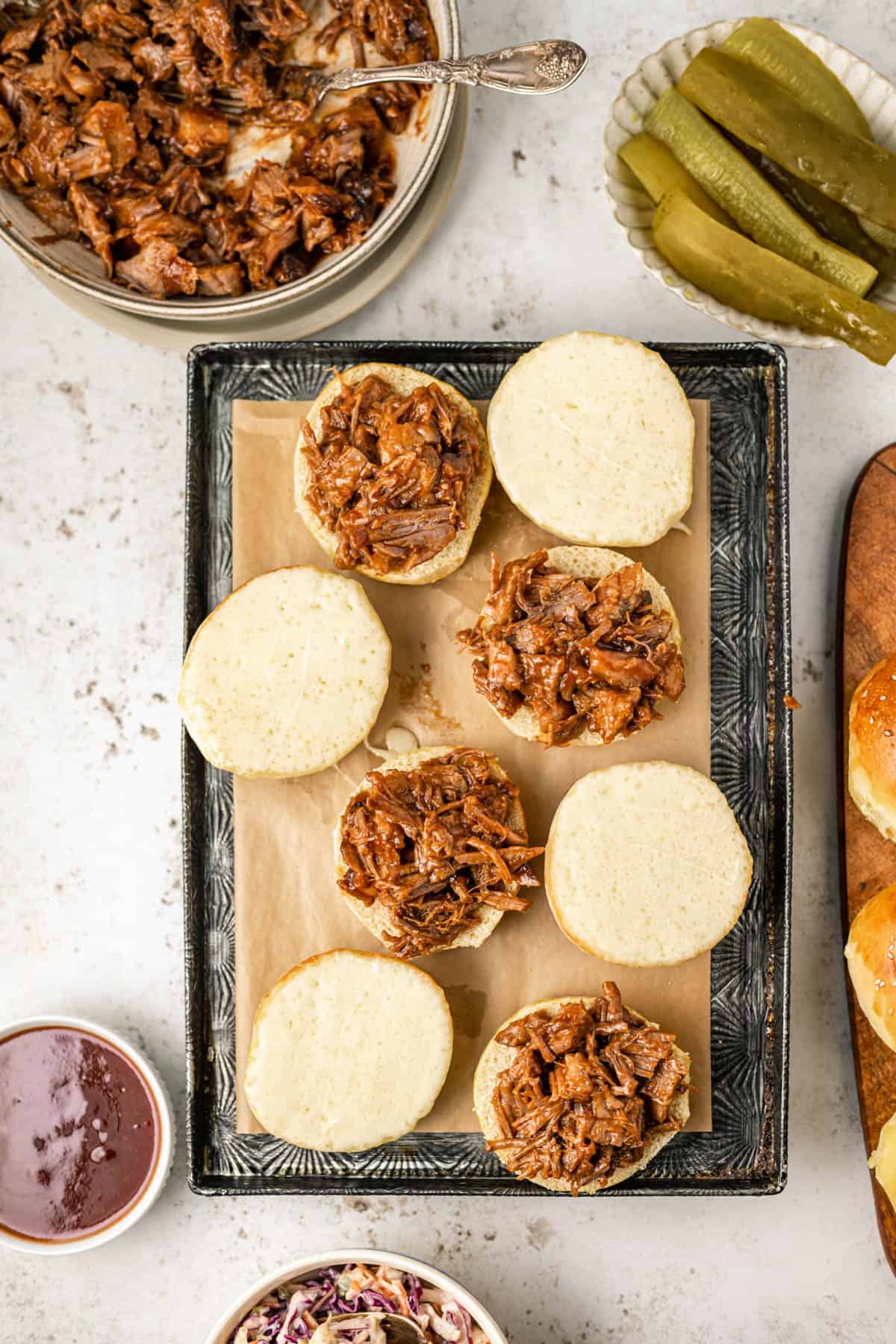 Buns with melted provolone cheese and shredded beef brisket on them.