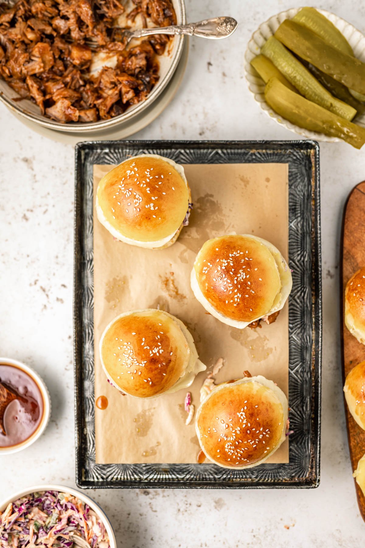 Topping bbq beef brisket sandwiches with a sesame bun.