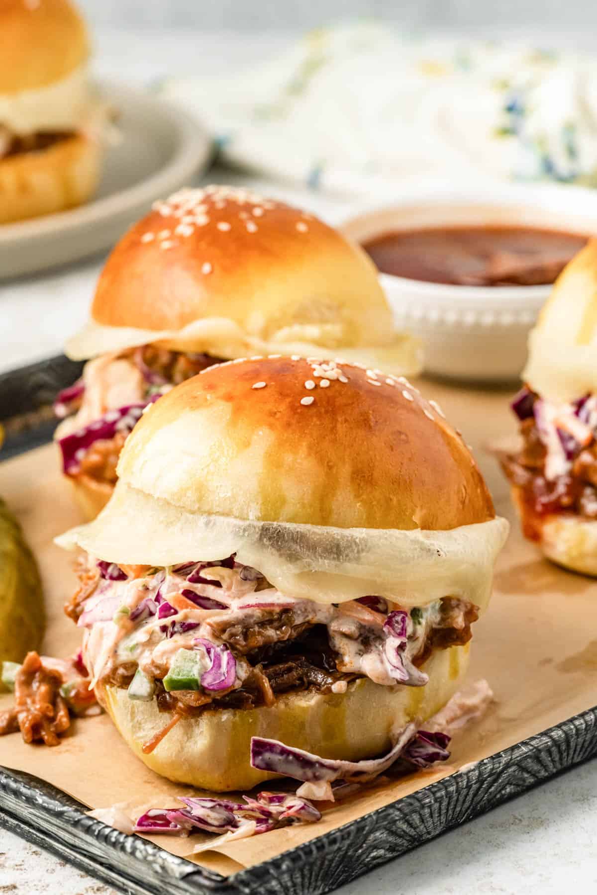 Beef brisket sandwiches on a baking sheet lined with parchment paper.