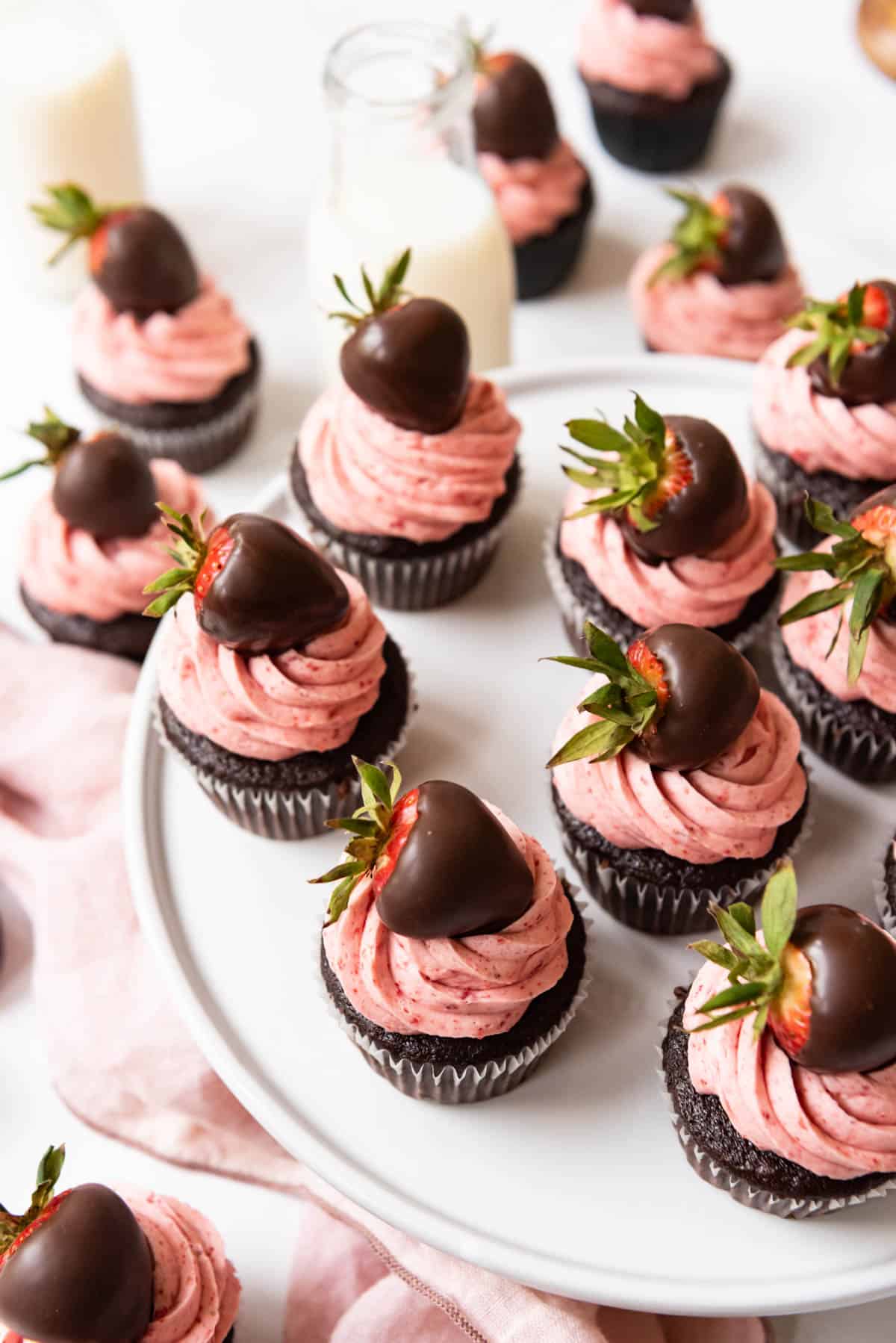 Chocolate covered strawberry cupcakes arranged on a white cake stand.