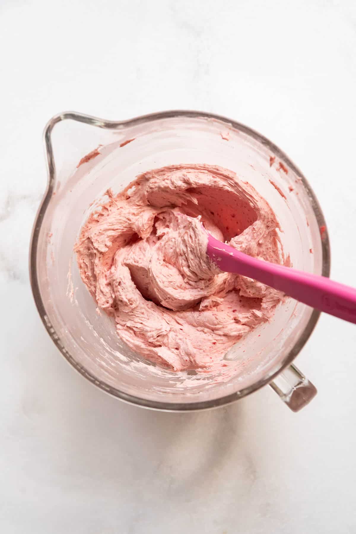Strawberry frosting in a large glass mixing bowl.