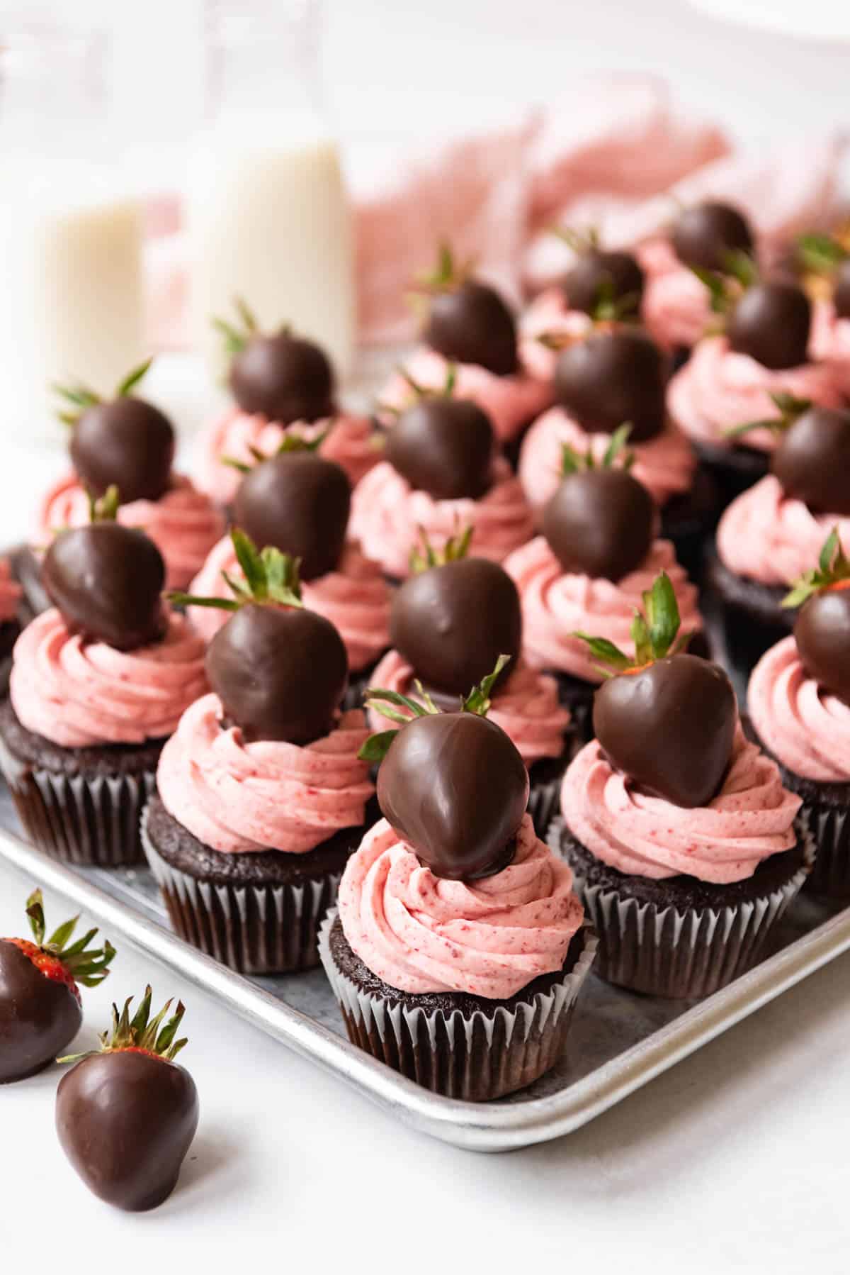 Rows of finished chocolate covered strawberry cupcakes decorated with chocolate covered strawberries on top.