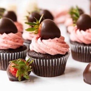 Chocolate covered strawberry cupcakes with a chocolate covered strawberry next to it.