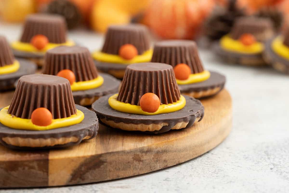 Fun Thanksgiving cookies that look like pilgrim hats on a wooden board.