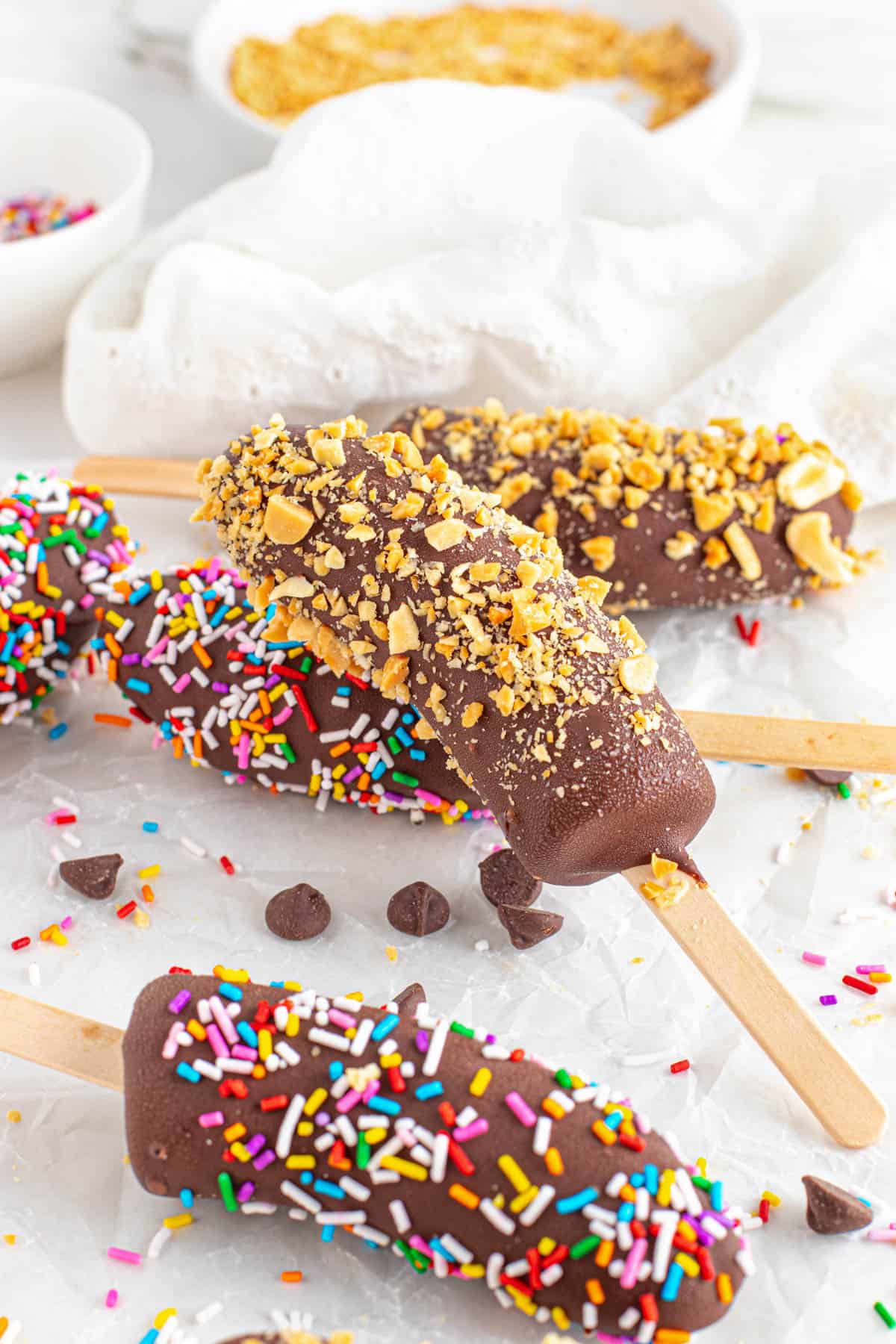 Chocolate covered bananas on sticks decorated with various toppings.
