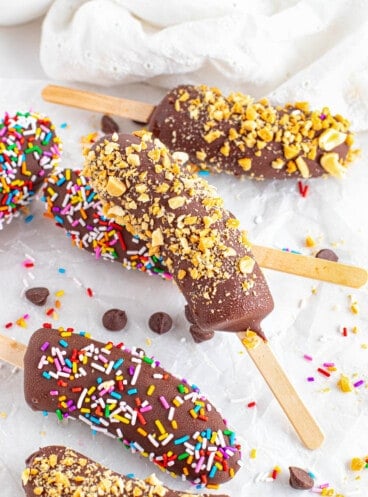 An image of frozen bananas topped with crushed peanuts and sprinkles.