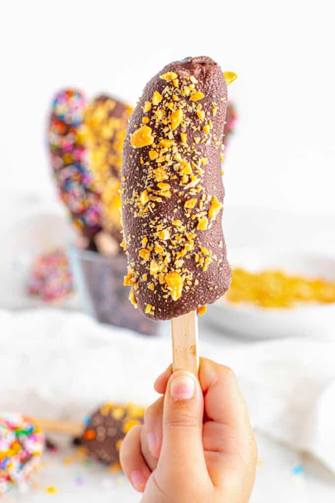A hand holding a frozen banana popsicle.