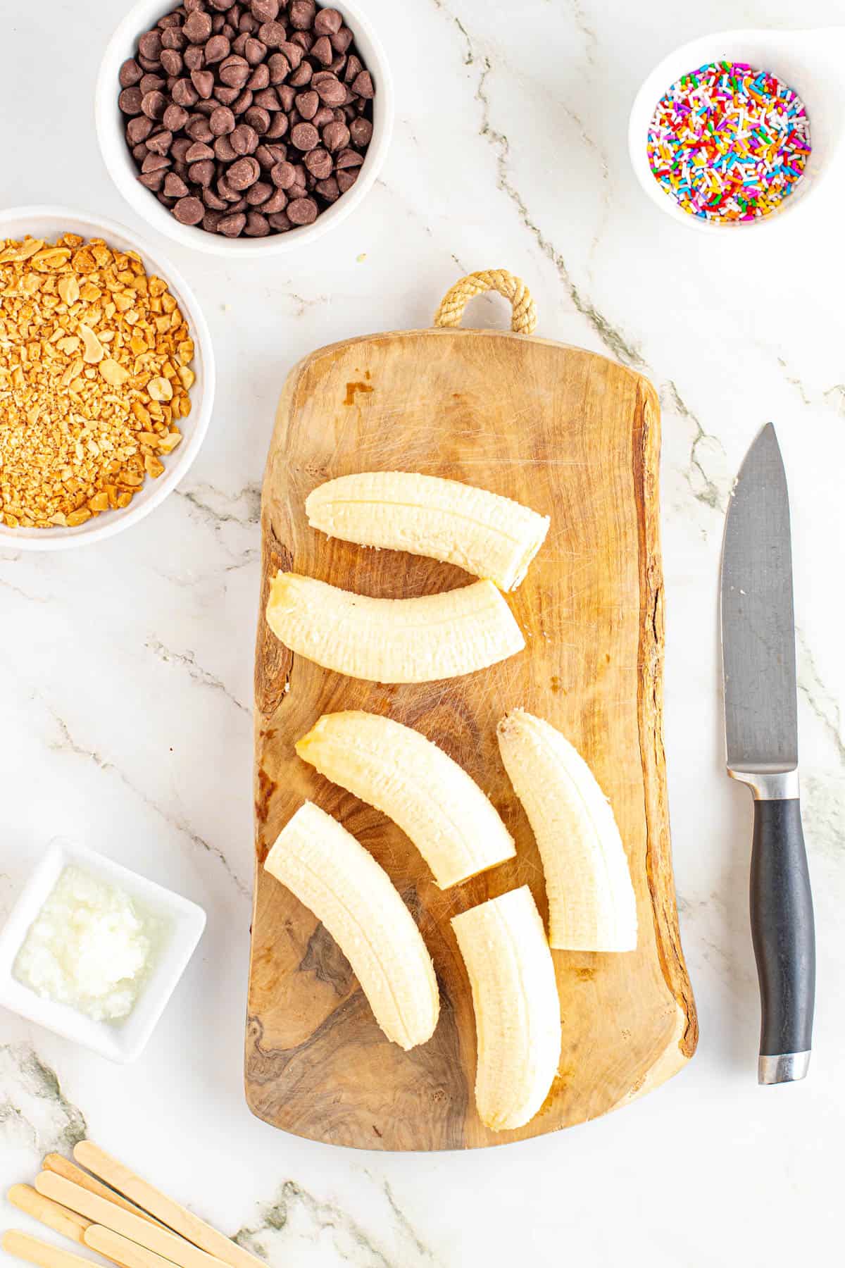 Bananas that have been cut in half on a wooden cutting board.