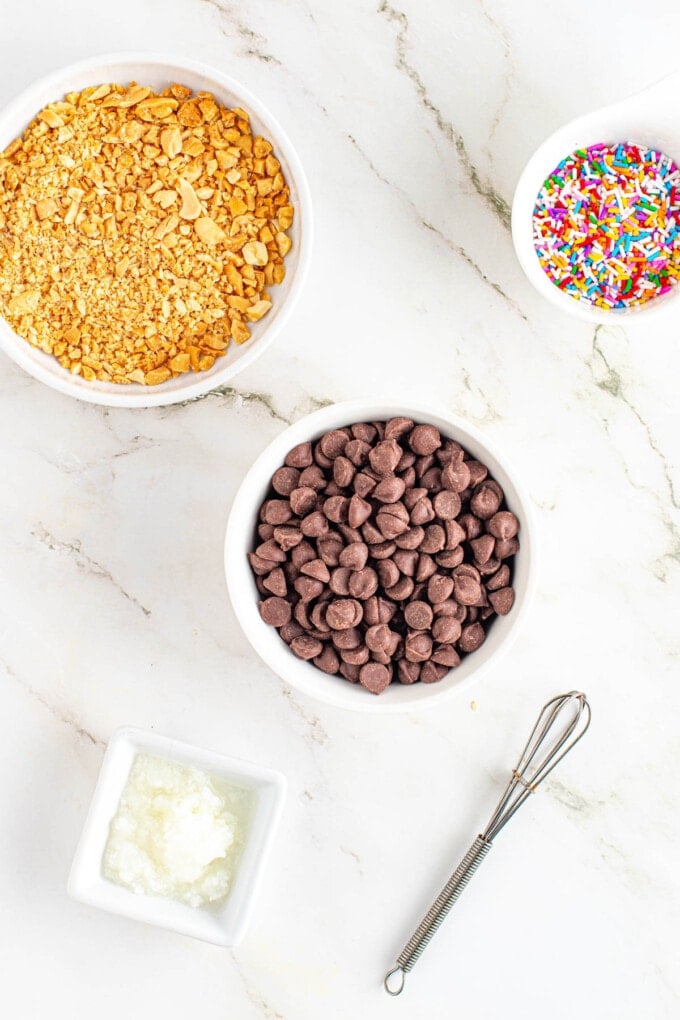 Chocolate chips, crushed peanuts, and rainbow sprinkles in bowls.