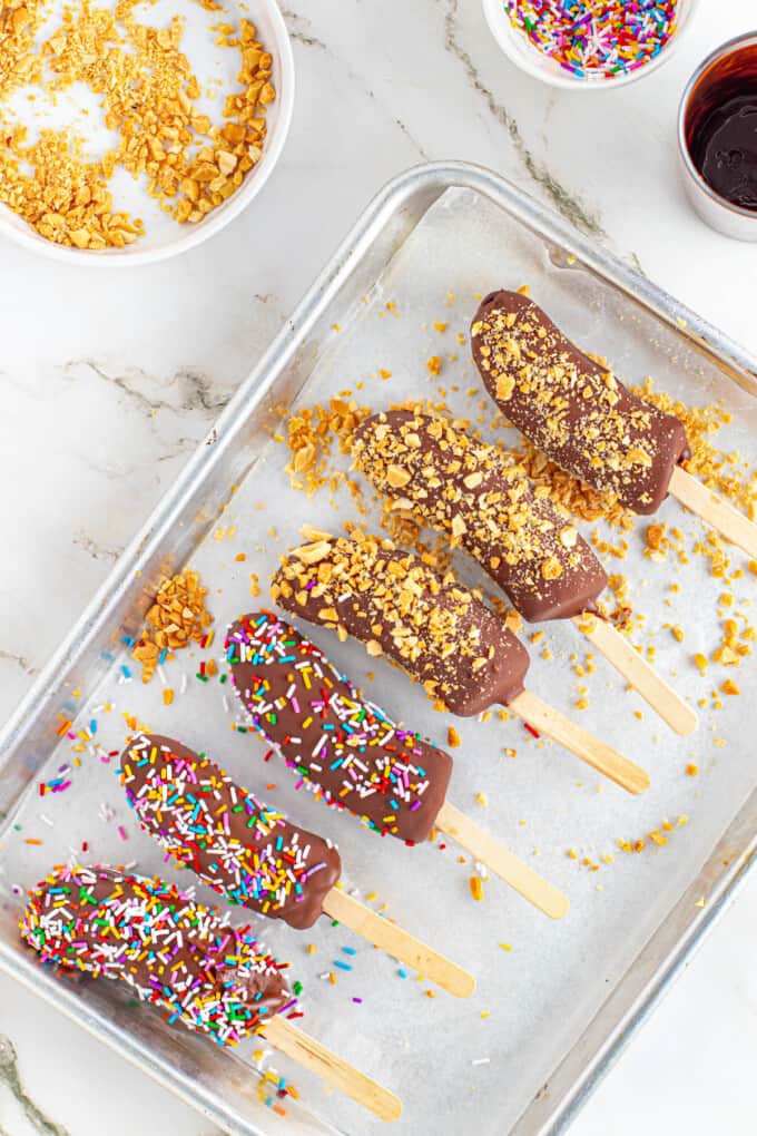 Decorated frozen bananas on a baking sheet.
