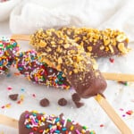 An image of frozen bananas topped with crushed peanuts and sprinkles.