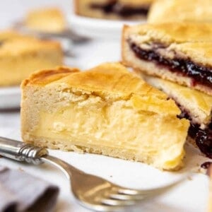 Slices of pastry cream and cherry jam filled Gateau Basque with a fork in front of them.