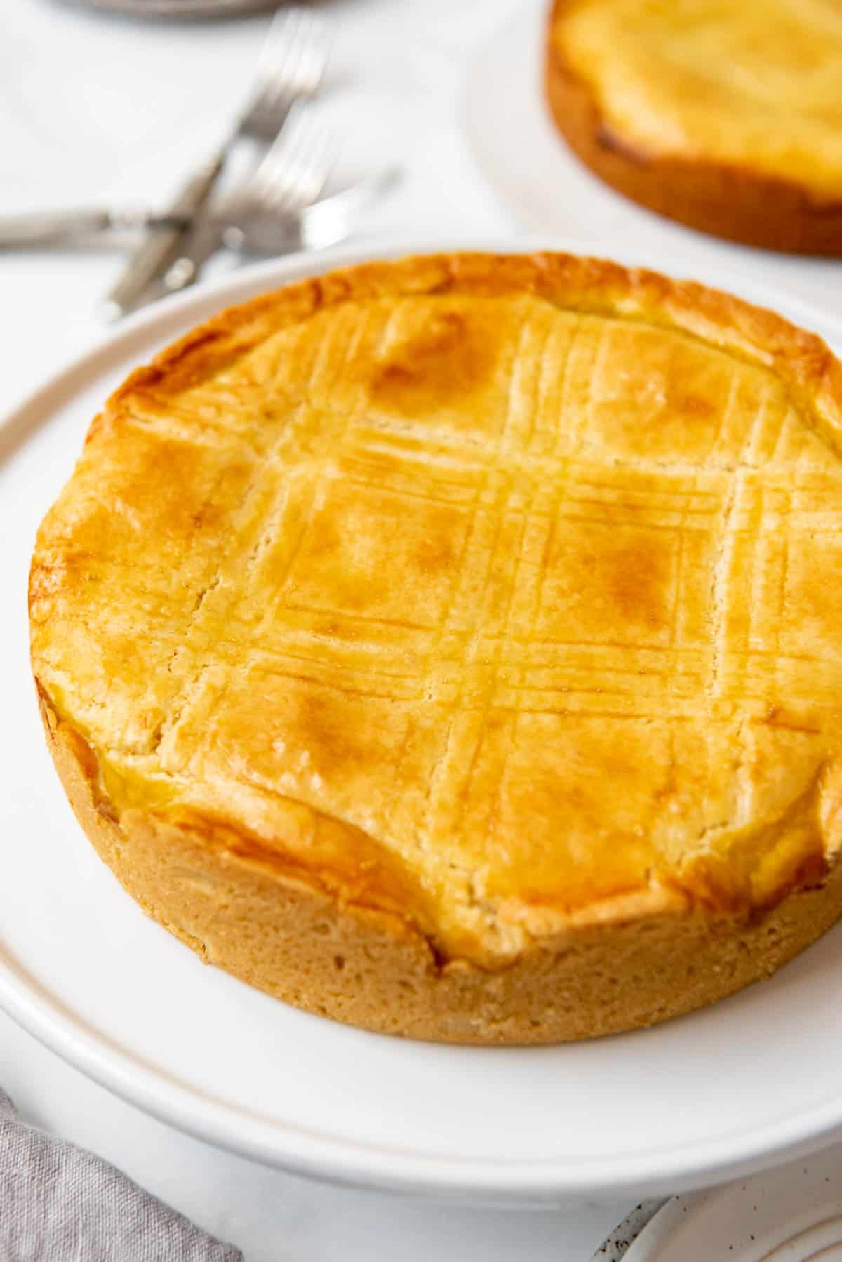 A baked Gateau Basque cake on a white cake stand.