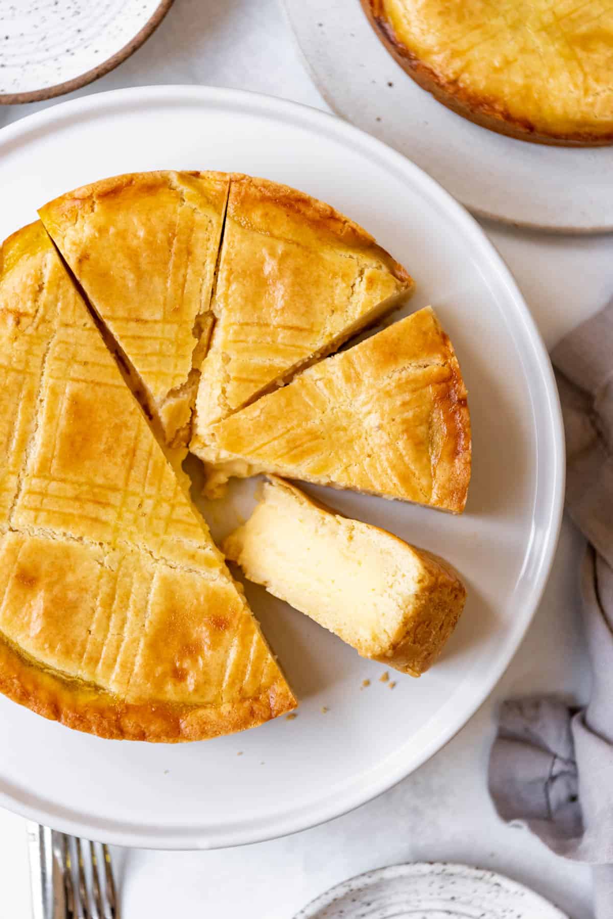 A Gateau Basque cake filled with pastry cream with one slice turned on its side to show the filling.