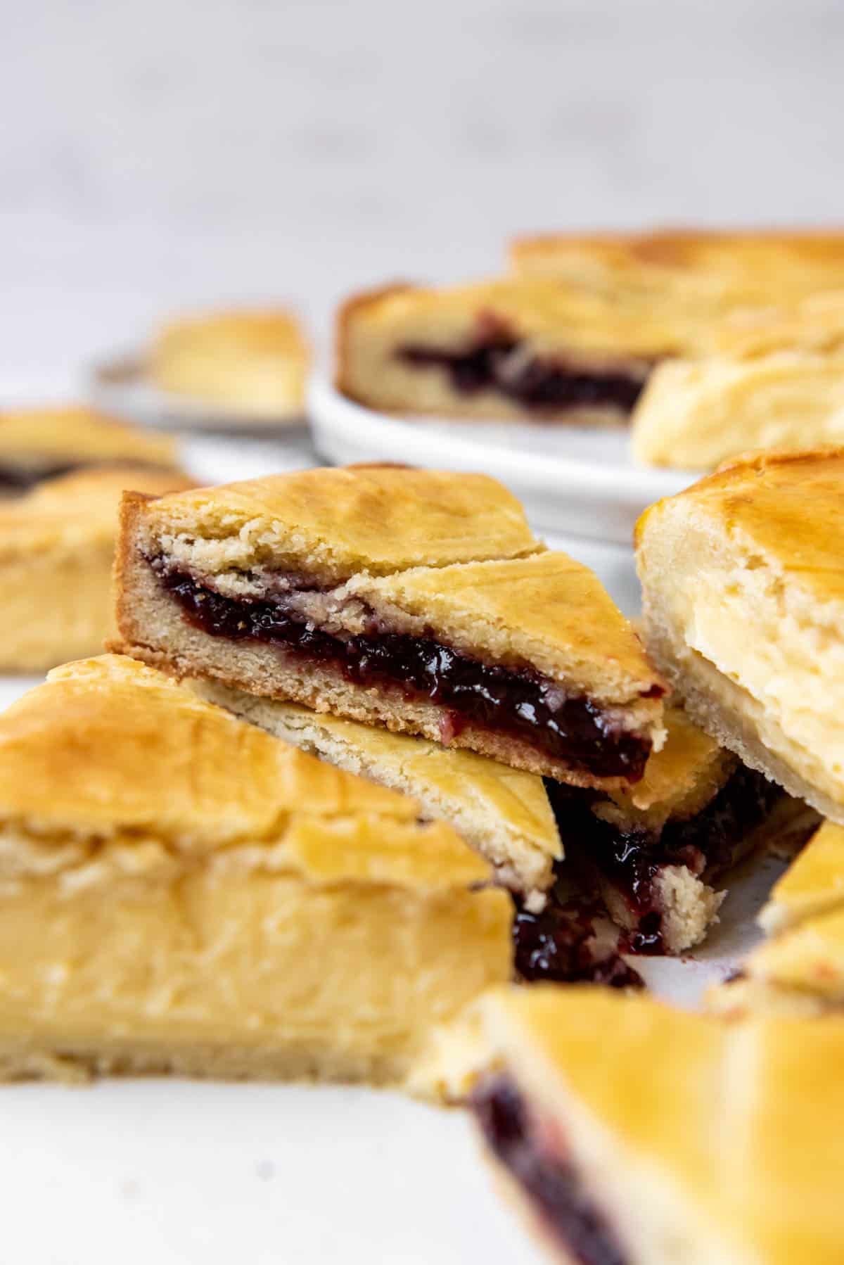 A slice of Gateau Basque filled with cherry jam on top of a Gateau Basque slice filled with pastry cream.