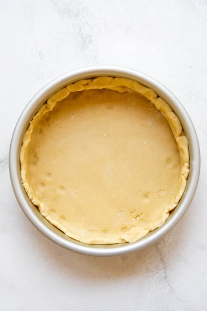 Lining a cake pan with a sweet pastry crust for a Gateau Basque Cake.