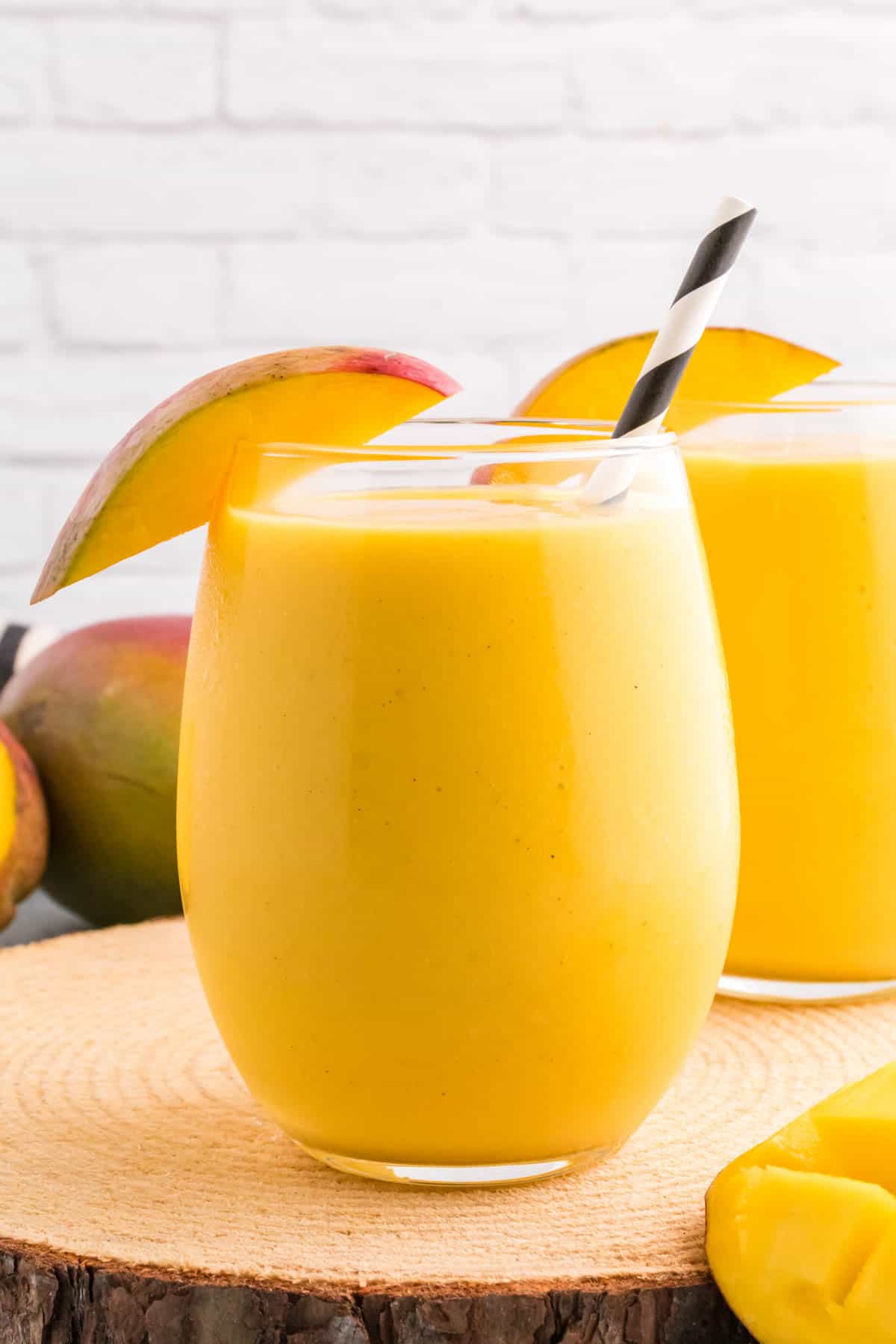 A glass of mango lassi with a slice of fresh mango for garnish.